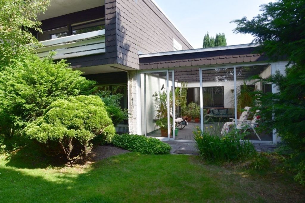 Blick vom Garten auf Haus mit Wintergartenanbau
