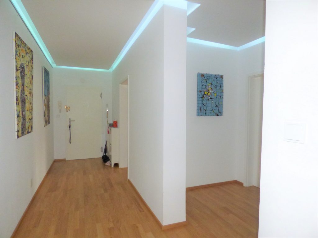 Wohnungsflur mit Holzboden, weiße Wände und indirekte Decken Beleuchtung
