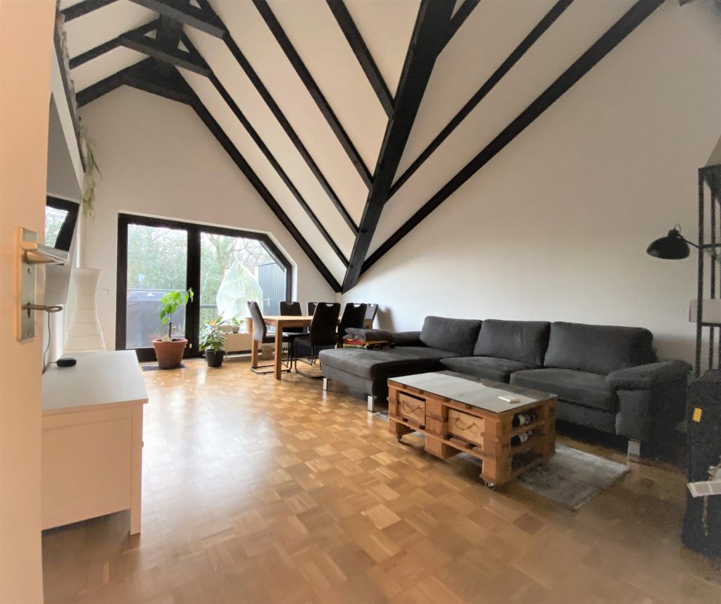 Wohnzimmer mit Dachschräge mit vielen dunklen Holzbalken