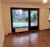 Raum mit Holzfußboden und einem Großen Fenster mit Blick in Wald
