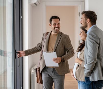 A young couple with a real-estate agent visiting an apartment for sale or for rent. Married couple buying an apartment. Real estate concept.